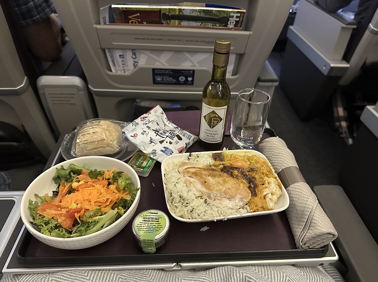 Das Menü auf dem United Airlines Premium Economy Flug von London Heathrow nach San Francisco: Salat, Hähnchen-Kichererbsen-Curry, Brötchen mit Butter und Wein. 