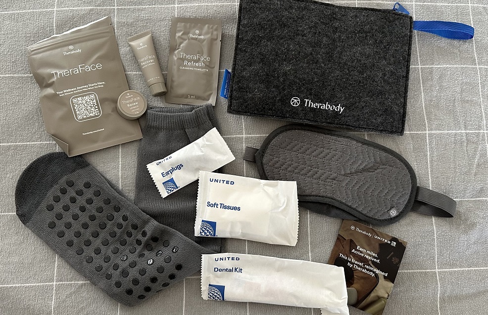 Das Therabody Amenity Kit in der United Airlines Premium Economy: Schlafmaske, Taschentücher, Ohrstöpsel, Zahnbürste, Socken und ein TheraFace Set bestehend aus Erfrischungstuch, Lippenbalsam und Handcreme